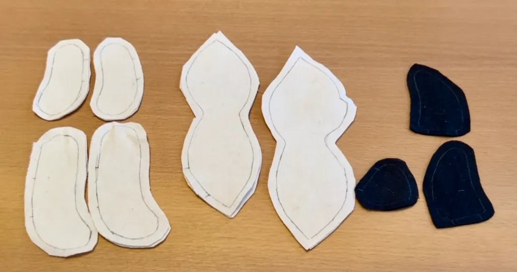 All of the pattern pieces cut out, minus the tail. This includes two arms, two legs, two front body, two back body in tan, and one snout, and two ears in dark brown.
