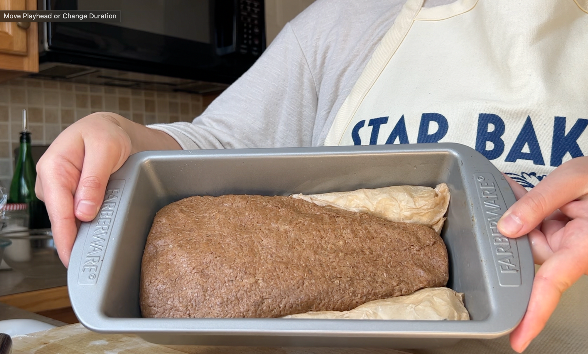 Black rye shaped in a loaf pan with parchment cones shaping the dough into a long triangle
