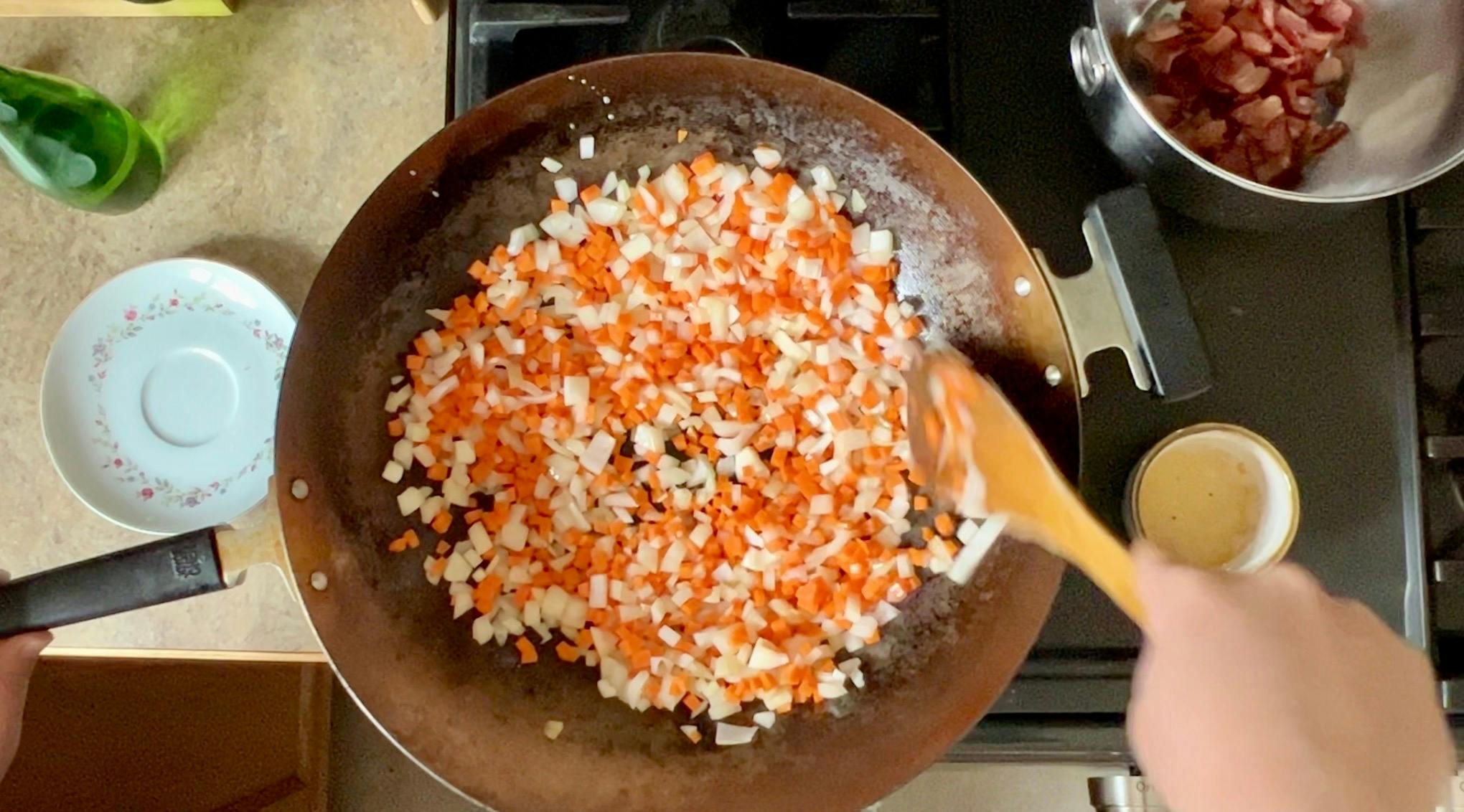 Carrots and onion cooking in a wok.