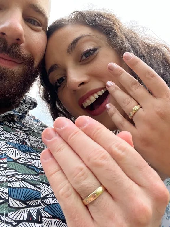A selfie of Josh and Katrina showing off their wedding rings and smiling.
