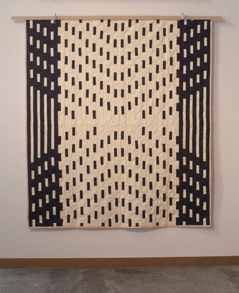 A black and white quilt with dashes and lines in a large symmetrical pattern