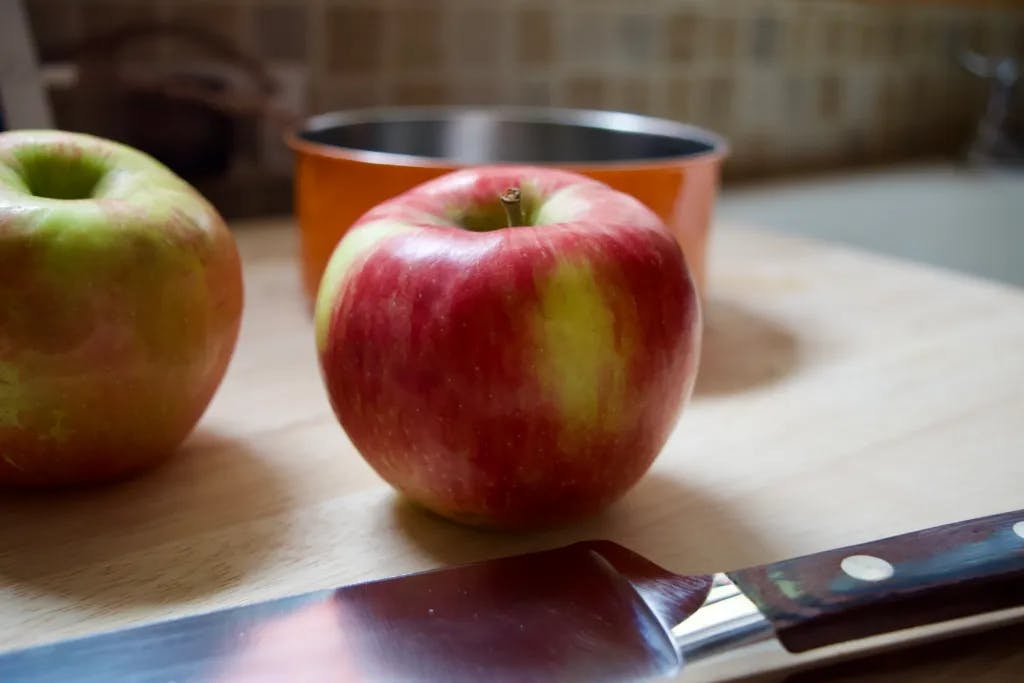 An apple and knife on a cutting board.