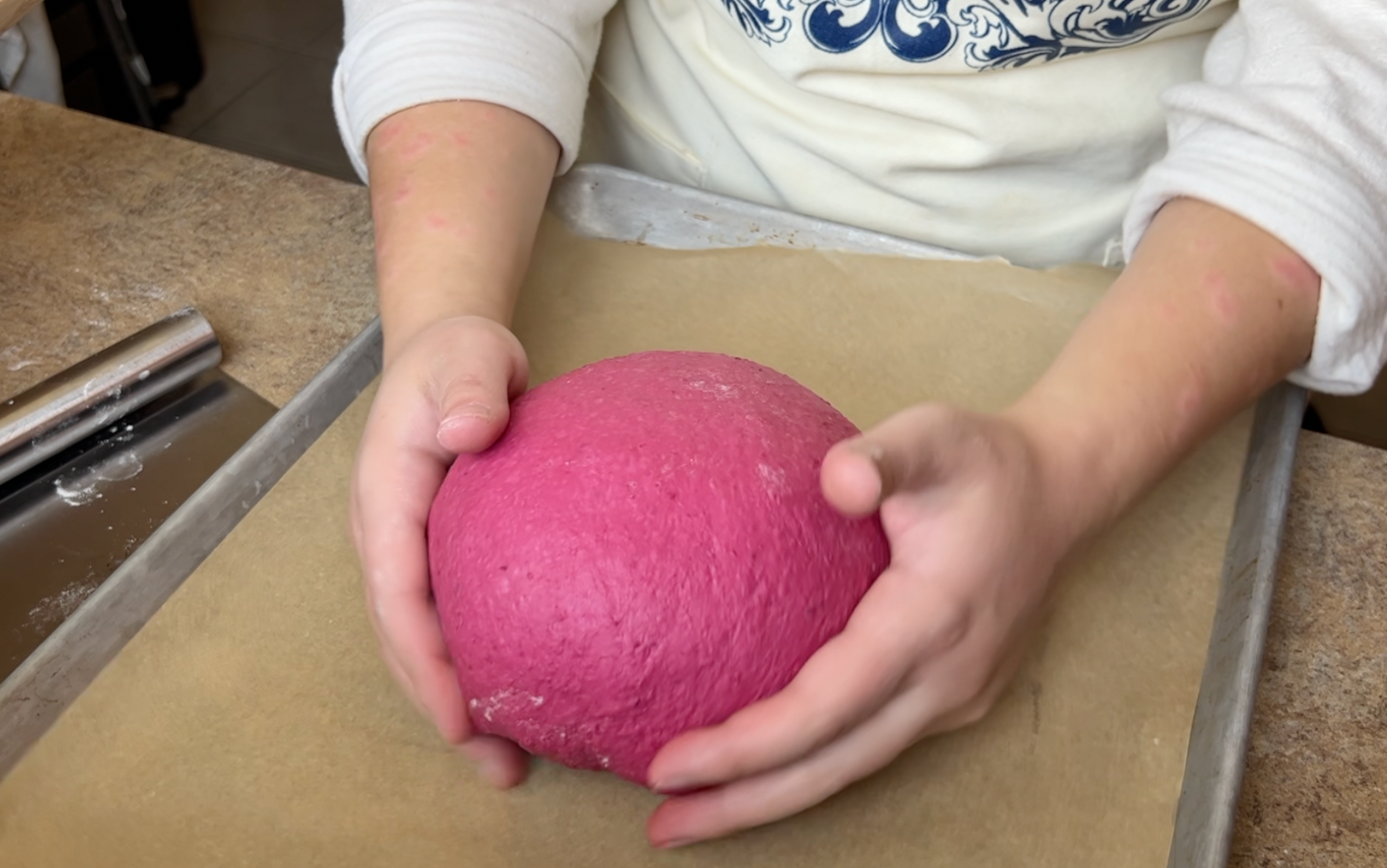 Putting the pink beet dough onto a sheet tray lined with parchment