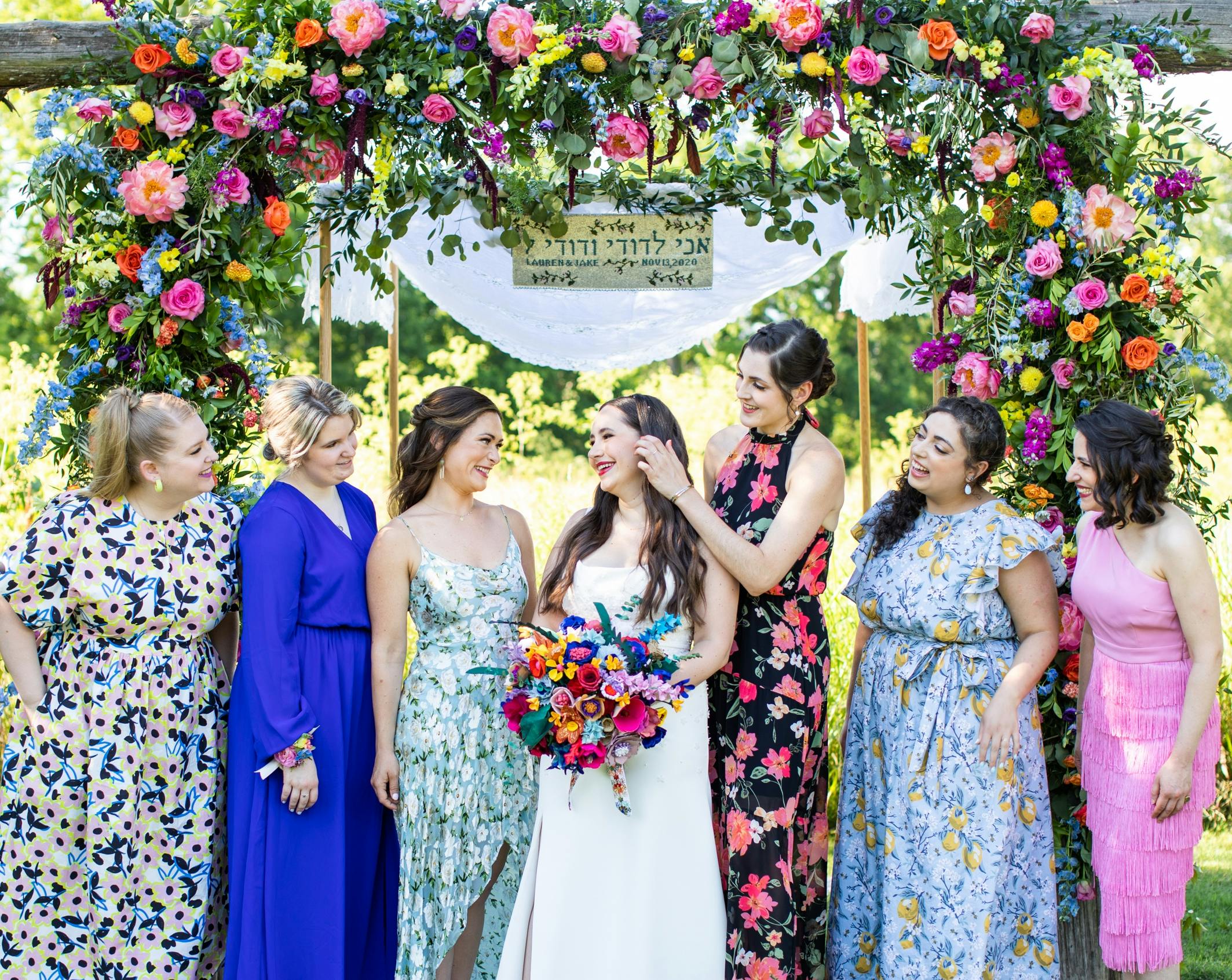 Lauren with her bouquet and her unofficial bridesmaids in front of the chuppah.