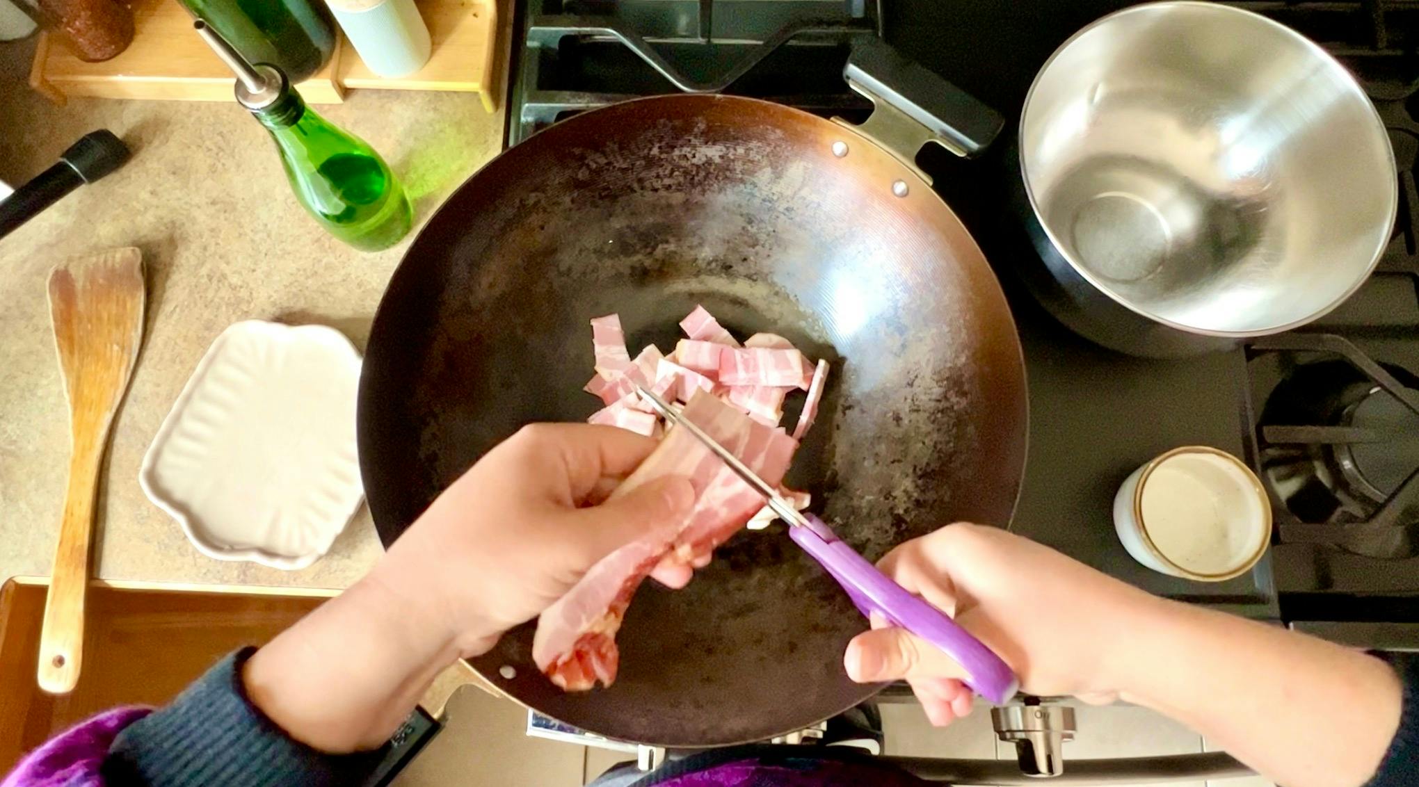 Cutting bacon into the wok.