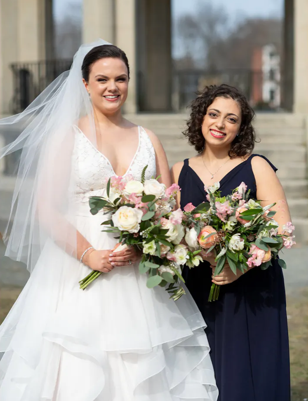 A bride and a bridesmaid (me!). I am wearing a navy dress and we are both holding bouquets