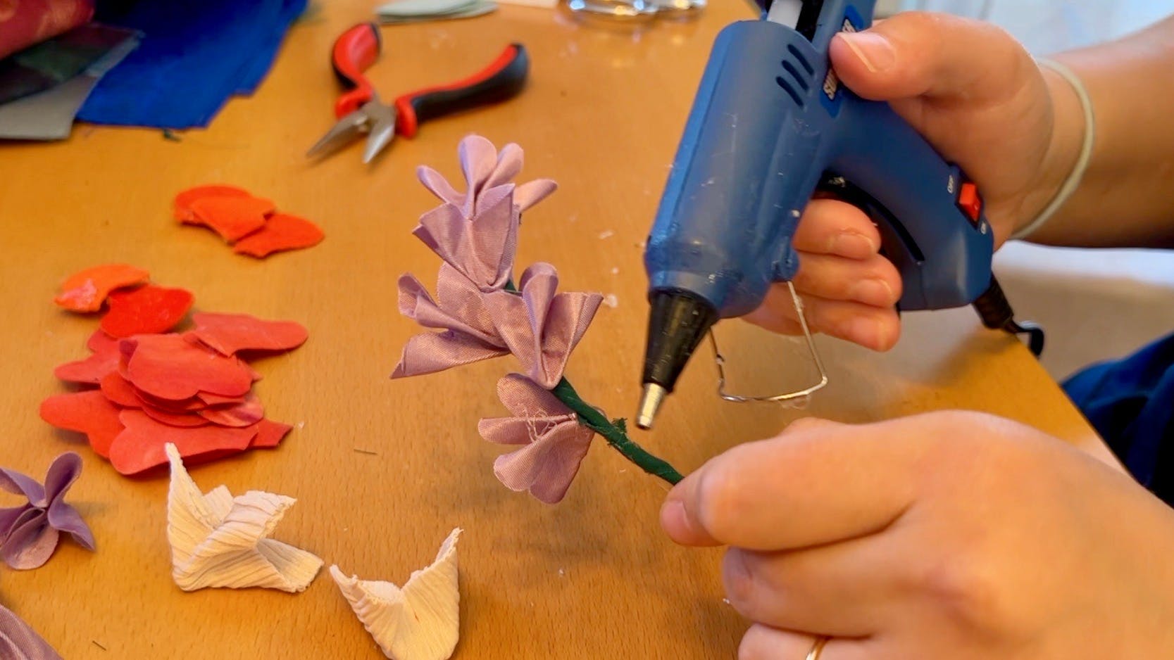 Glueing tiny purple flowers to a stem.