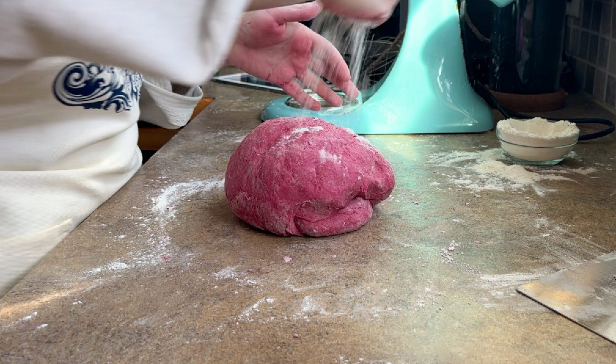 Dusting more flour into the pink dough