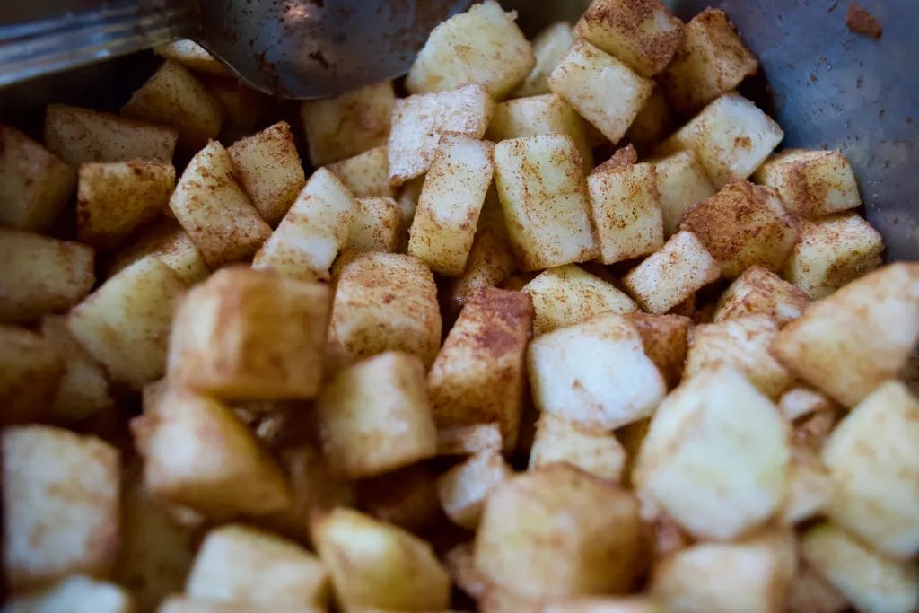 Cut apple chunks covered in cinnamon in a bowl.