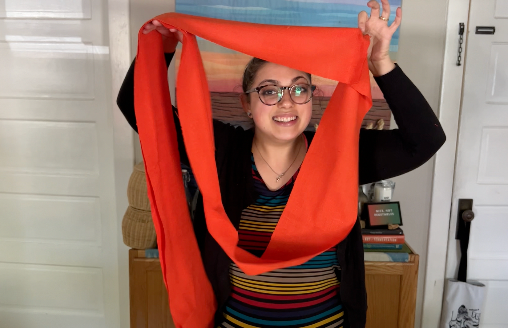 Holding up a loop of fabric for one of the tiers and smiling through it like it's a window