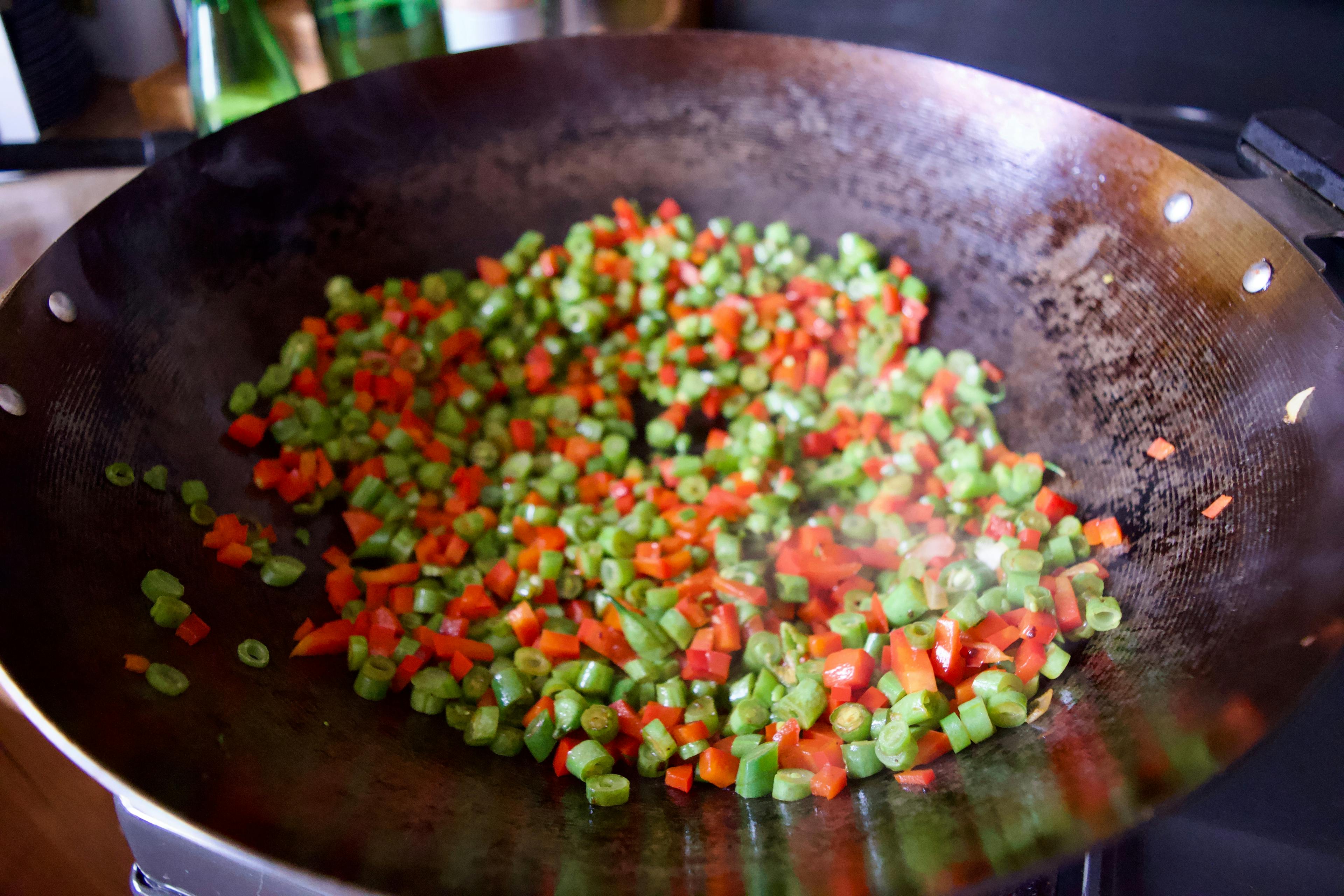 Red pepper and green beans cooking in a wok.