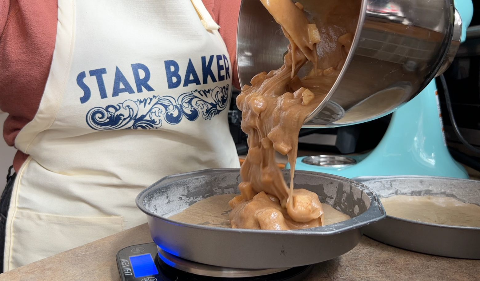 Pouring batter from a bowl into a cake tin.