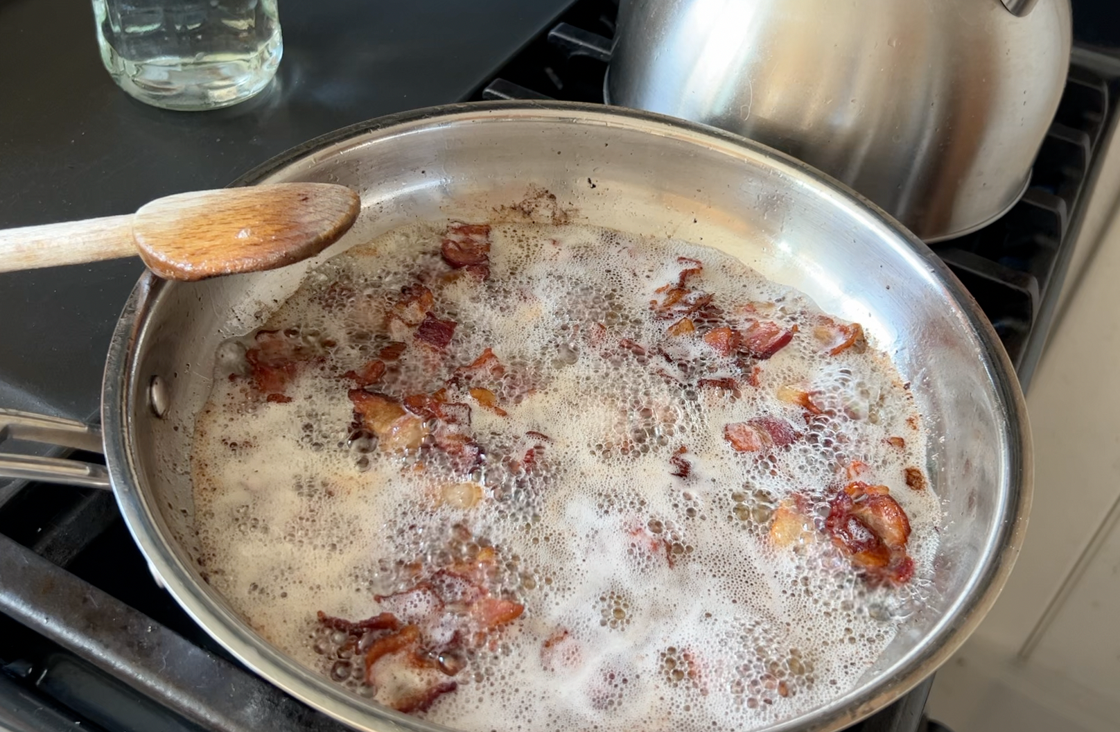 Bacon lardons cooking in a pan.