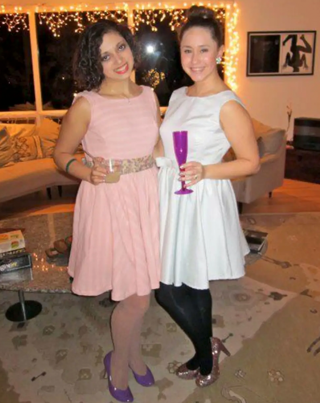 Lauren and I holding champagne and wearing our dresses we made for her 21st birthday. Her's is white and mine is pink. She is wearing black tights and glittery heels, I am wearing nude fishnets and purple heels.