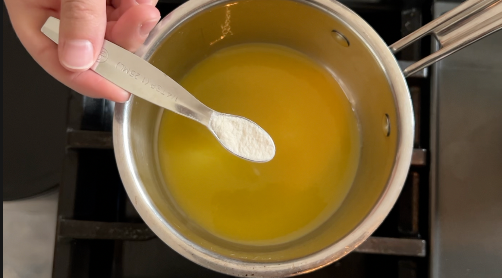 Mango puree in a saucepan on the stove and a teaspoon of agar agar, a white powder.
