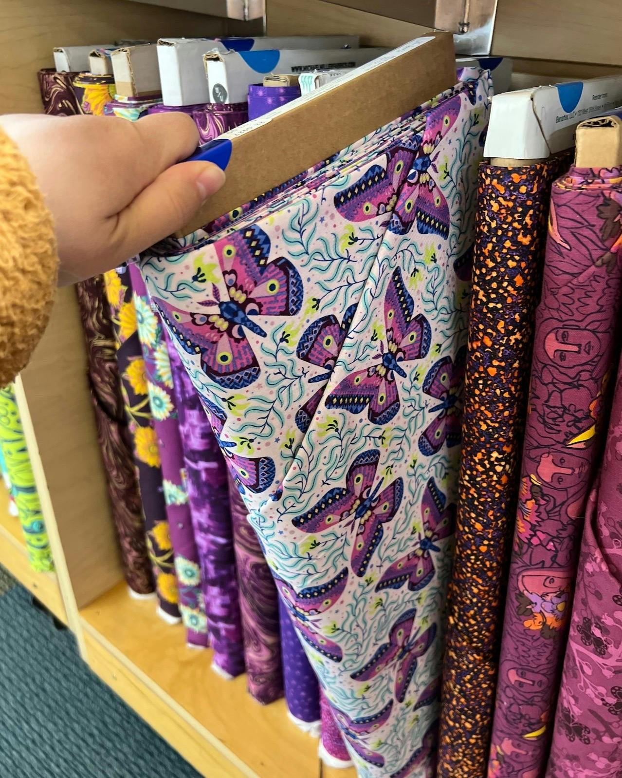 Purple and blue butterfly fabric on the shelf at a fabric store. 