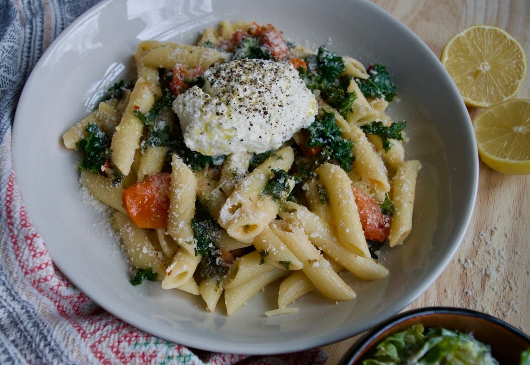 A bowl of pasta and veggies with a dollop of ricotta cheese on top.
