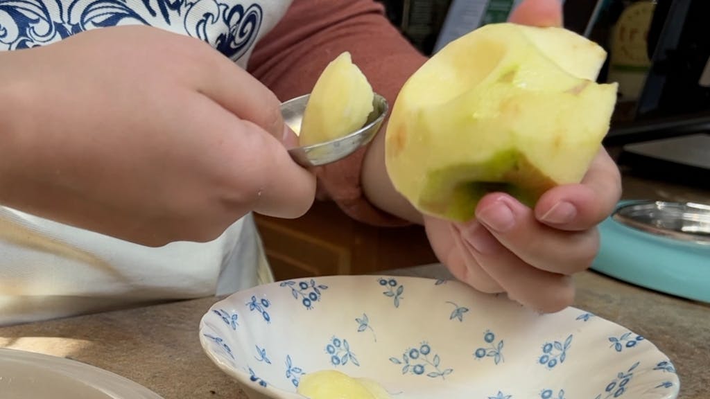 Trying to carve an apple with a tablespoon measure.
