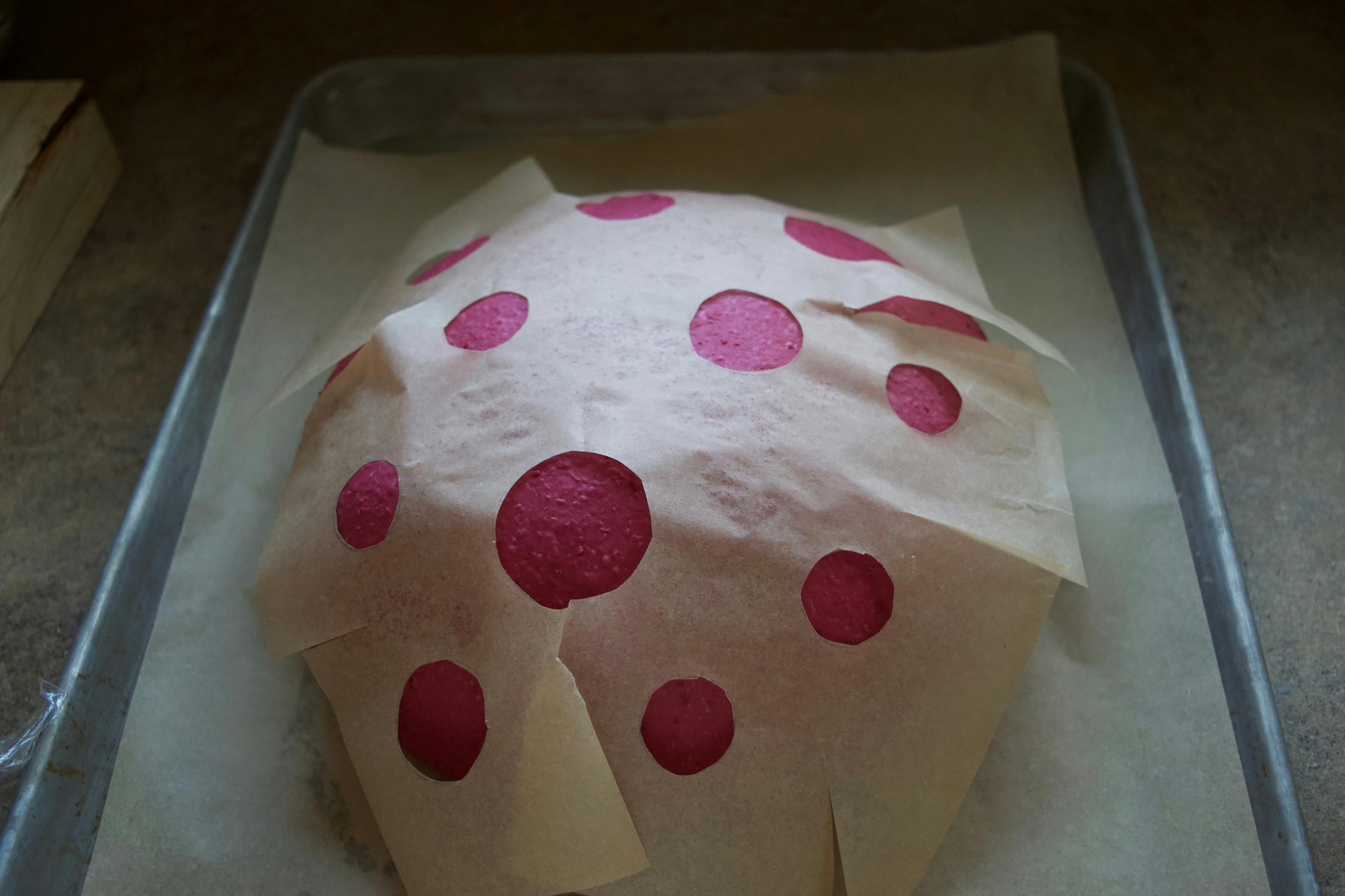 The beet bread with parchment laid on top with many holes cut out