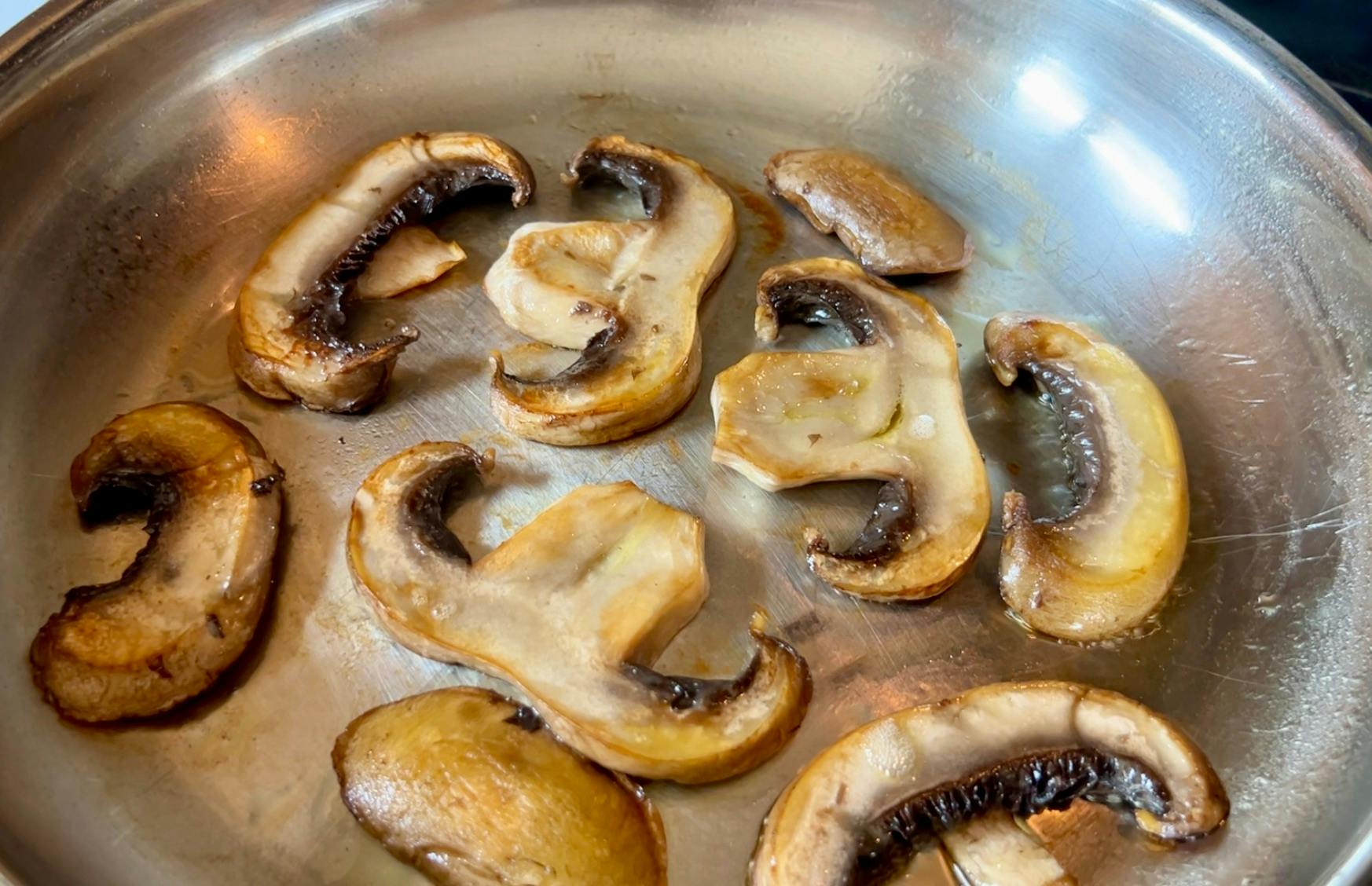 Golden brown mushrooms in a stainless steel pan